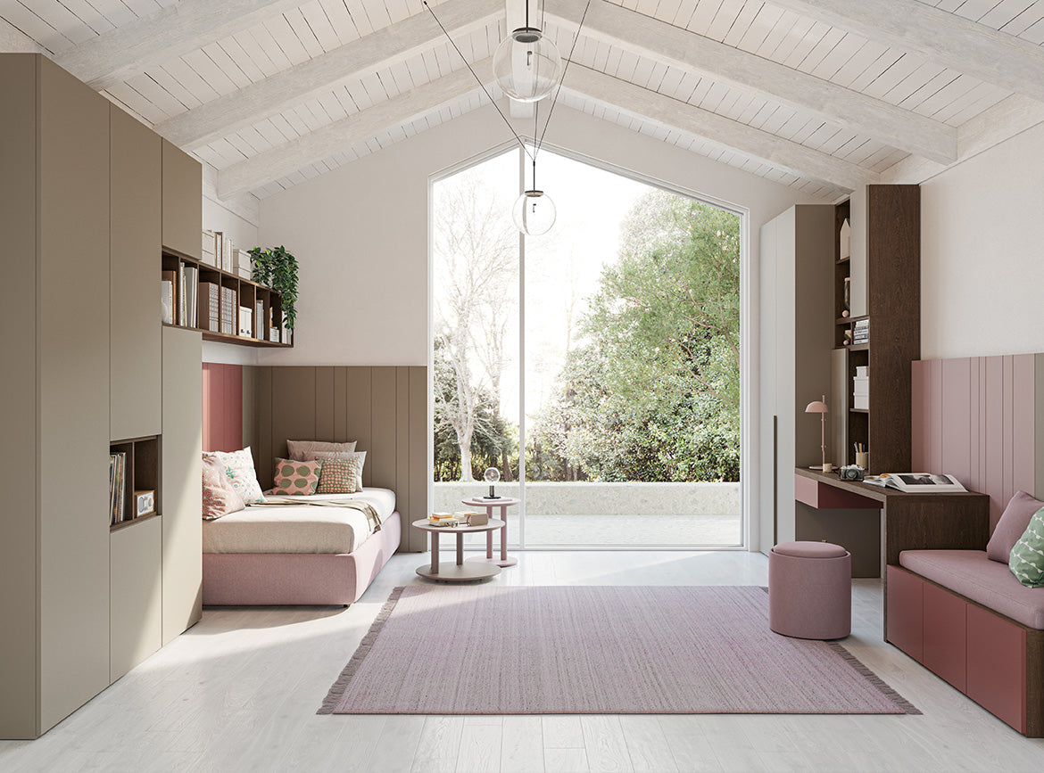 Cameretta luminosa con letto singolo rosa e beige, ampio armadio, scrivania con libreria, tappeto rosa e grande finestra panoramica.
