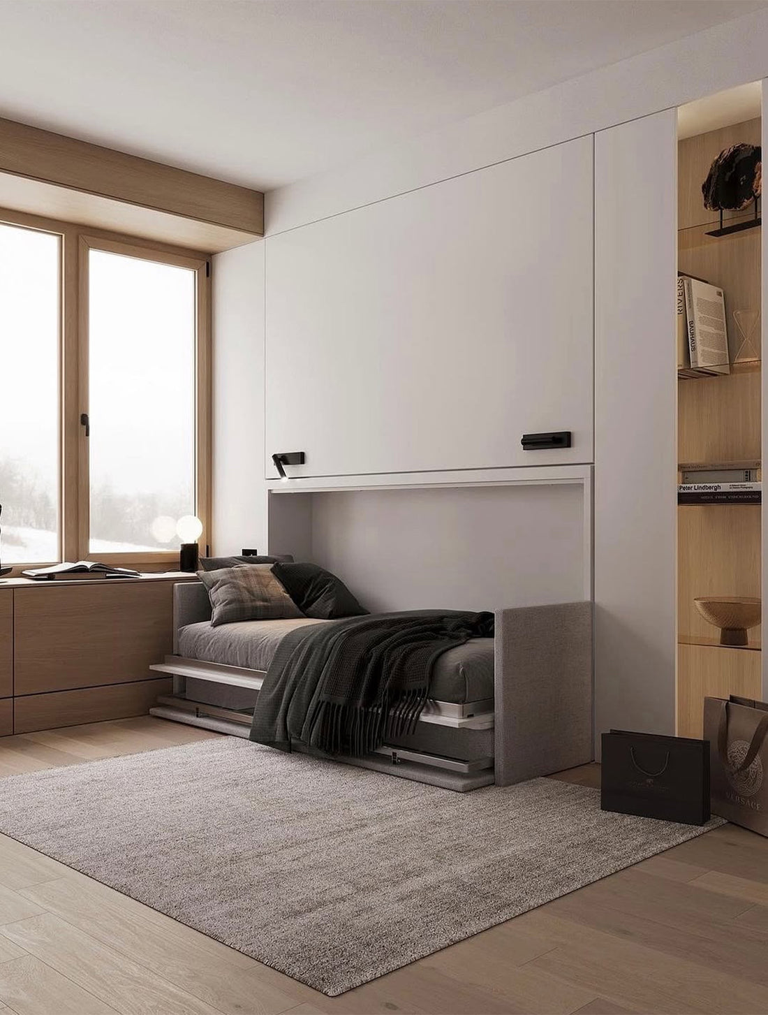 Letto singolo a scomparsa integrato in mobile bianco, con divanetto grigio, cuscini a quadri e vista su finestra in legno.
