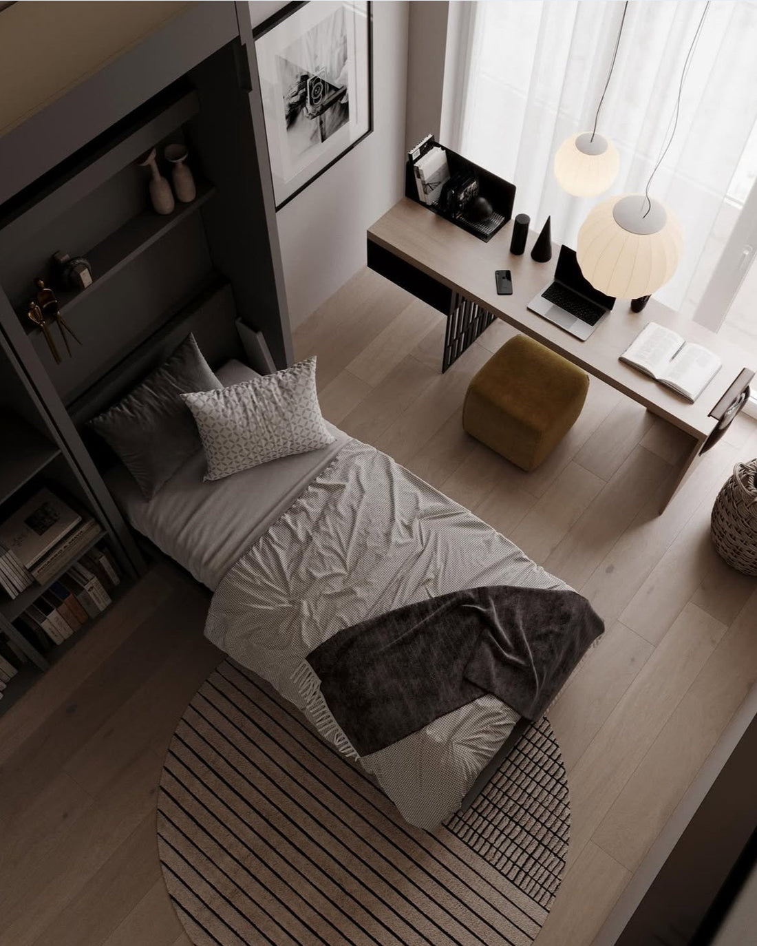 Camera moderna compatta con letto singolo grigio, scrivania in legno chiaro con lampade a sospensione bianche e tappeto rotondo a righe.